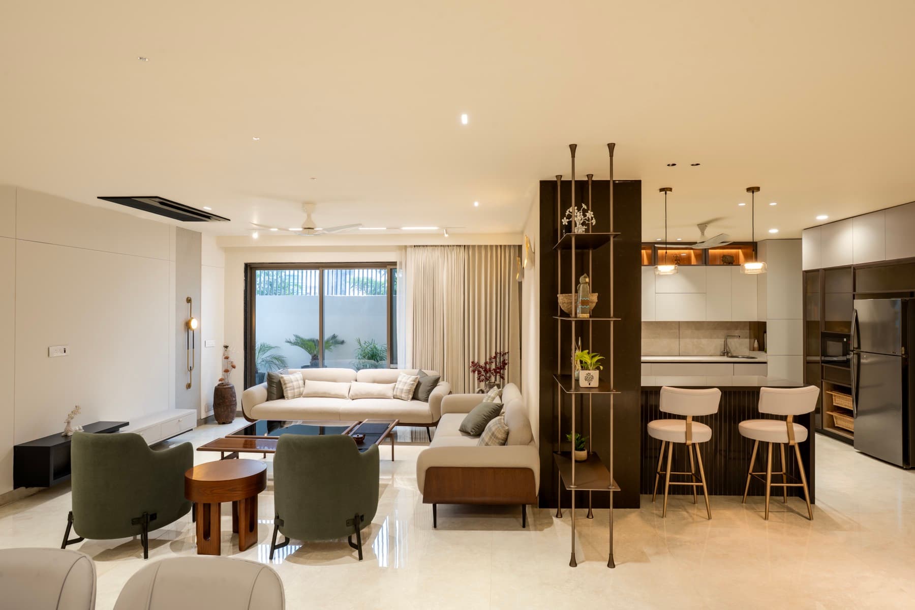 Open living room and island kitchen divided by a dark column with bronze rod shelving