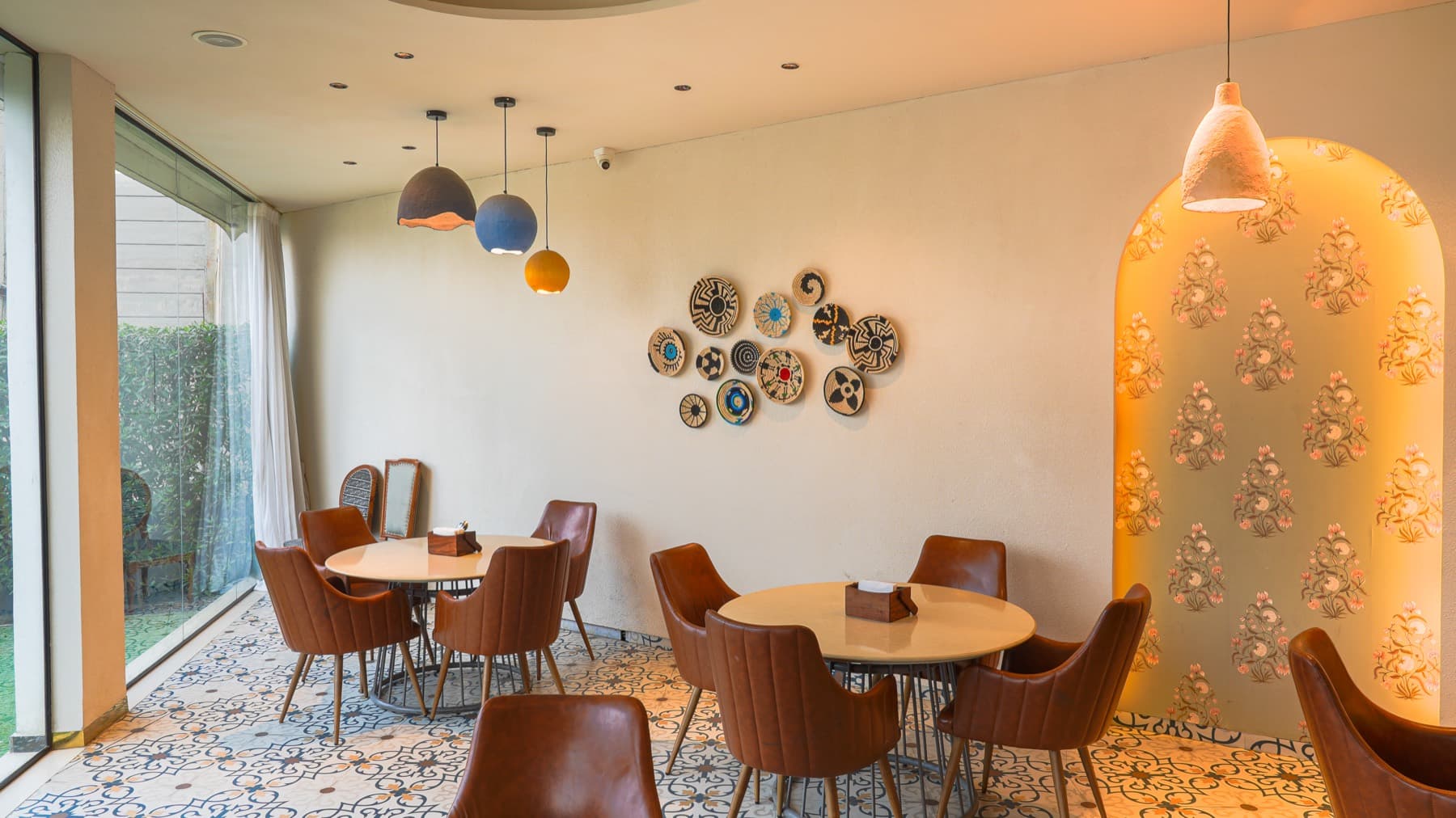 Dining room with tan leather chairs, patterned tile floor and a lit arched niche of floral print