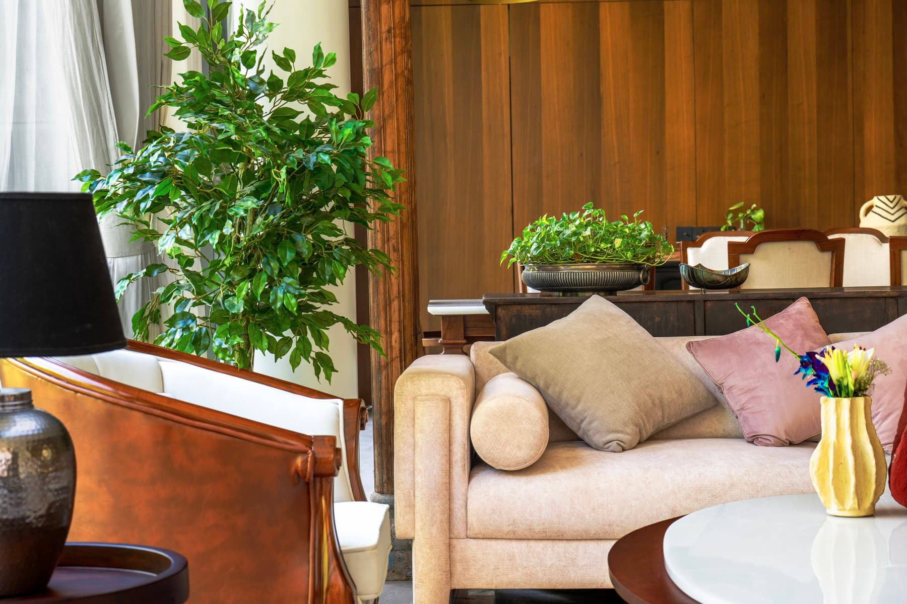 Living lounge with timber-panelled dining beyond at The Holiday Home, a family home in Hisar designed by Black Ant Studio