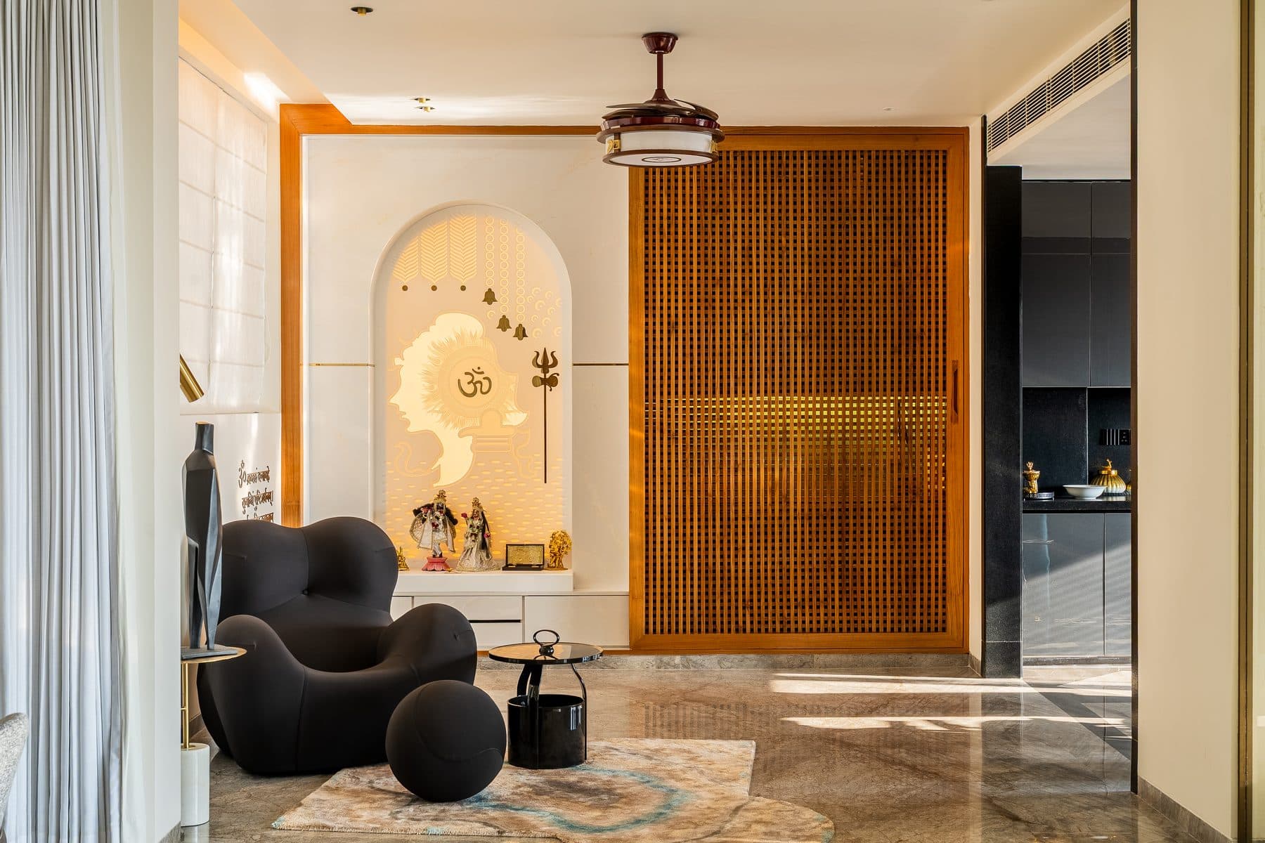 Pooja arch with a backlit laser-cut Om panel and deity figurines, the timber batten screen slid aside