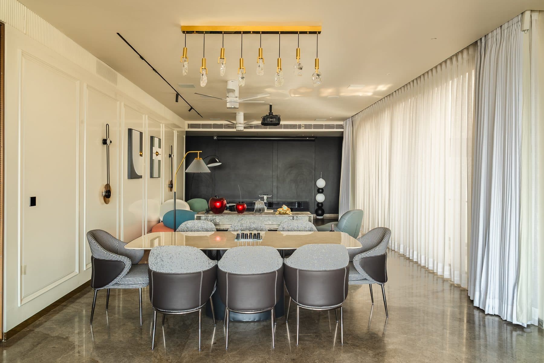 Dining room with houndstooth and grey chairs, raw-crystal pendants on a brass bar and a charcoal feature wall