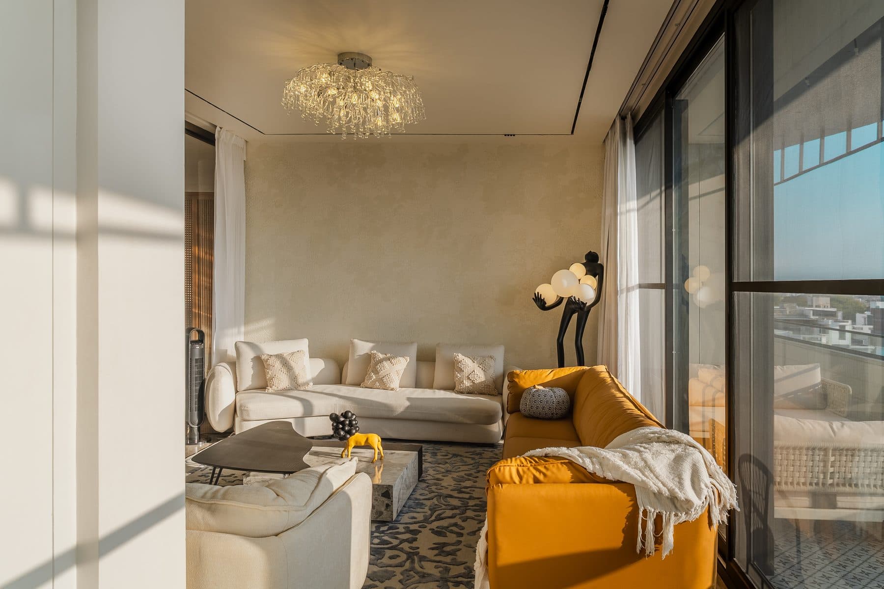 Informal lounge in low sun: cream boucle sofa against Venetian plaster, a black figure lamp holding white globes